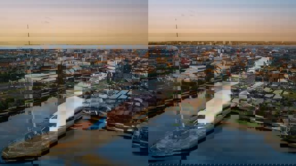 An aerial view of the Glasgow Science Centre at dusk. The building is on a peninsula in the Clyde river, with the city skyline in the background.