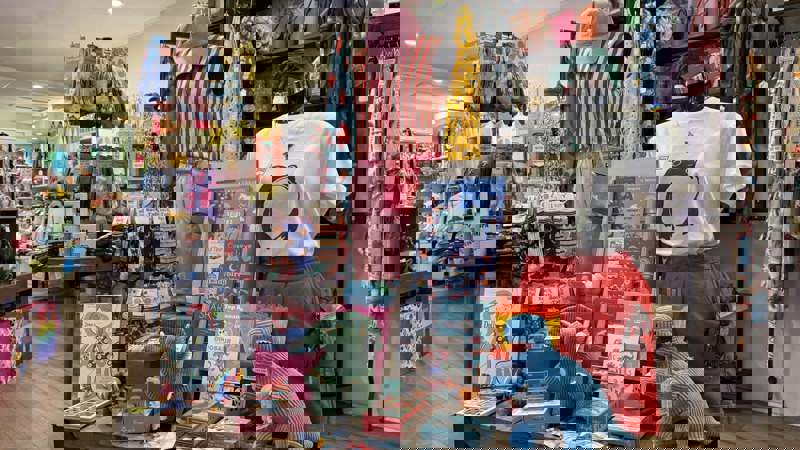 A display of eclectic items inside the Pink Poodle Boutique, including toys, books, and colourful clothing on mannequins.