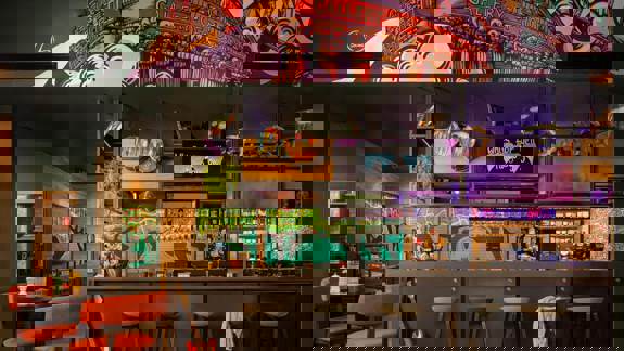 Colourful social lounge at Moxy Glasgow SEC with bold décor, illuminated signage, relaxed seating, and musical-themed artwork creating a vibrant atmosphere.