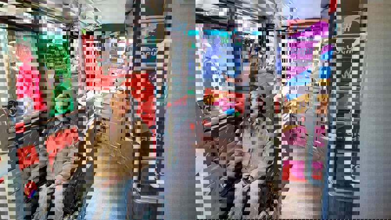 A person in a wheelchair on an accessible city sightseeing bus, with the interior of the bus and a ramp area visible.