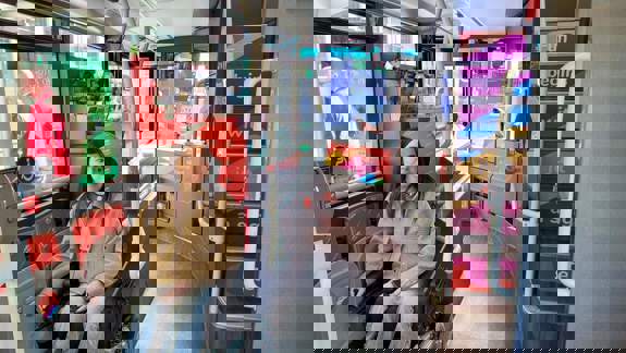 A person in a wheelchair on an accessible city sightseeing bus, with the interior of the bus and a ramp area visible.