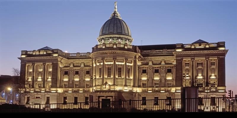 The Mitchell Library building at dusk, with its grand neoclassical architecture and illuminated dome against a deep blue sky.
