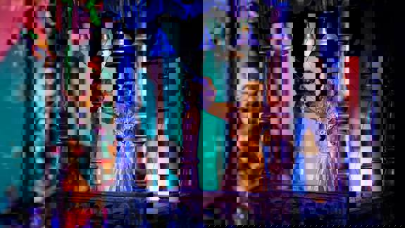 A close-up of a wooden puppet figure in an ornate, dark wooden structure with bells and strings.