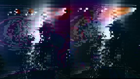 A drummer is silhouetted by bright lights on stage at the King Tut's Wah Wah Hut venue.