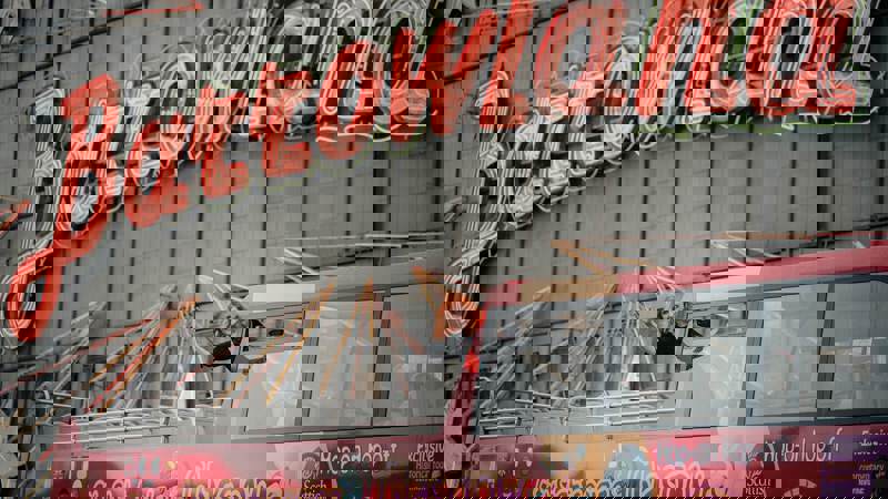 A red-haired woman waving from a red tour bus in front of the illuminated "Barrowland" sign.