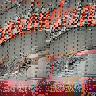 A red-haired woman waving from a red tour bus in front of the illuminated "Barrowland" sign.