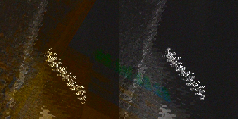 A neon sign for "SWG3" glows on the top of a brick building at night.