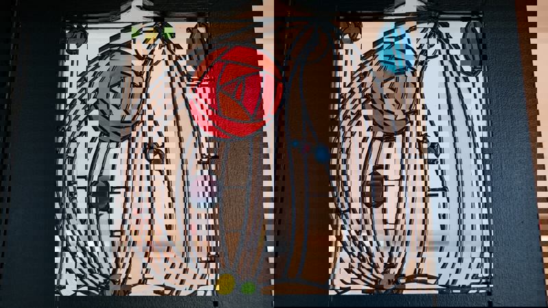 A close-up of a vibrant stained-glass panel with a stylized red rose, set into a dark wooden frame.