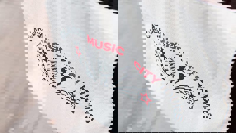 A close-up of a white tote bag with "Glasgow Music City Tours" and a microphone logo.