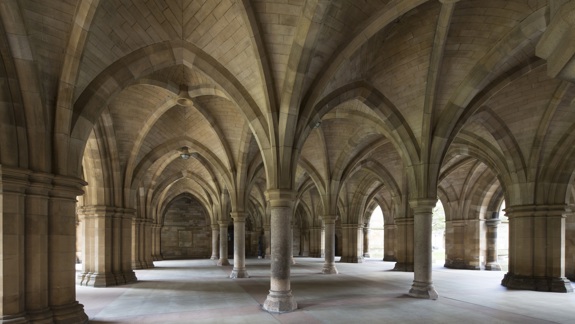 The cloisters at the University of Glasgow has Gothic-style arches and vaulted ceilings, featuring tall columns and soft natural light filtering through arched openings.
