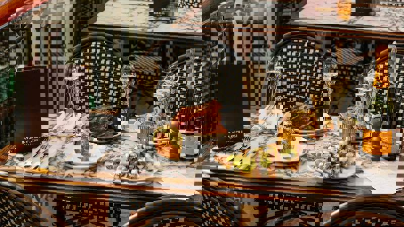 An elegantly set outdoor dining table at Maison by Glaschu, featuring champagne and various beautifully presented food dishes, hinting at a luxurious experience.