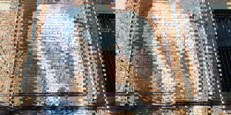 A large mural of a male musician wearing sunglasses and holding a guitar painted on a brick building wall.