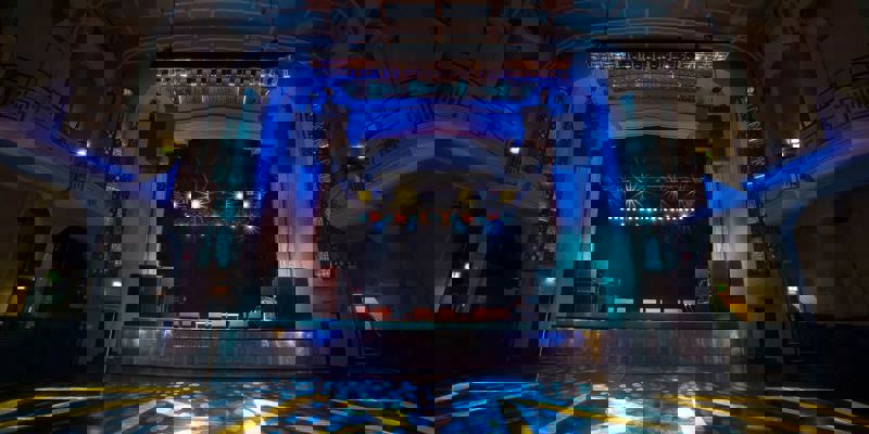 The O2 Academy Glasgow, showing its grand art deco interior with colourful stage lighting and empty dance floor before a concert.