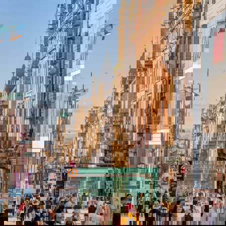 Bustling Buchanan Street in Glasgow with shops and pedestrians under a sunny sky.