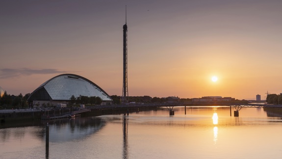 The Glasgow Science Centre and the Glasgow Tower at sunset, with a reflection of the buildings and sky in the River Clyde.