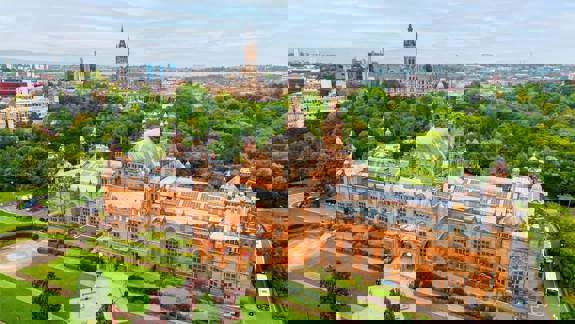 An aerial view of the grand, red sandstone Kelvingrove Art Gallery and Museum set within large green parklands.