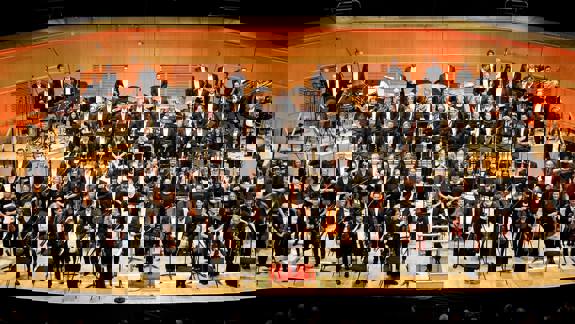 The Royal Scottish National Orchestra on stage at the Glasgow Royal Concert Hall, standing to receive applause. 