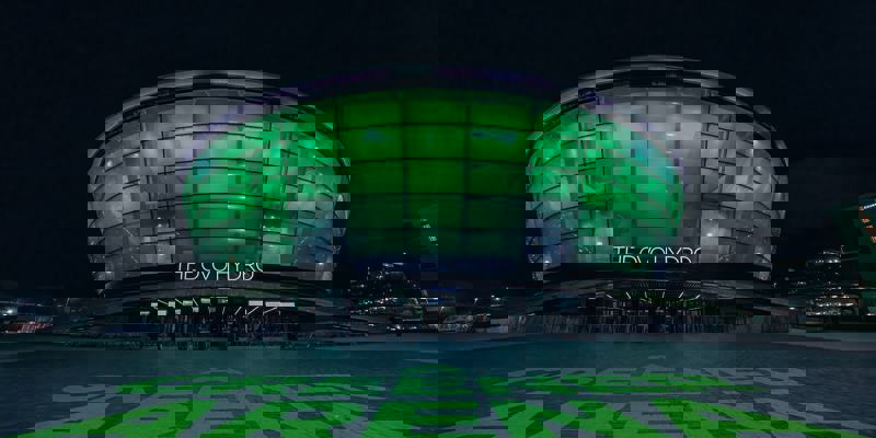 The OVO Hydro arena lit in green at night with “A Greener Arena” text projected on the ground outside.