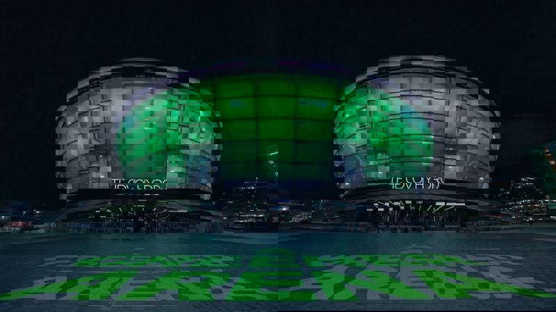 The OVO Hydro arena lit in green at night with “A Greener Arena” text projected on the ground outside.