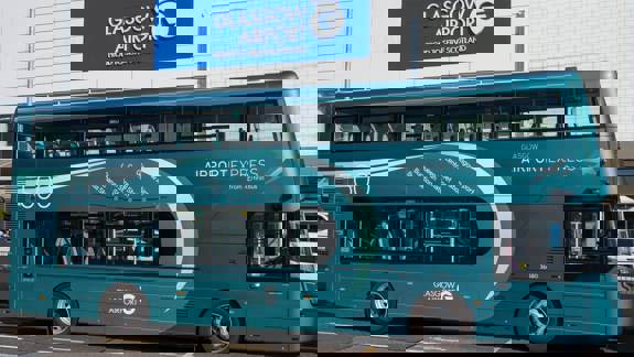 A turquoise First Bus double-decker bus for the Glasgow Airport Express 500 service parked in front of the main terminal building at Glasgow Airport.