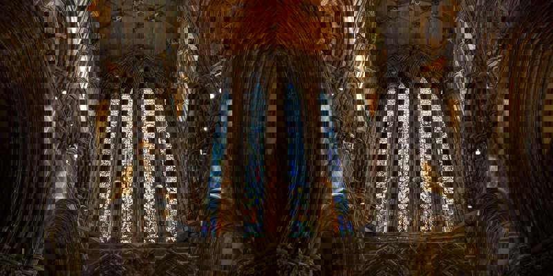 Interior of Glasgow Cathedral with tall stained glass windows and vaulted stone arches.
