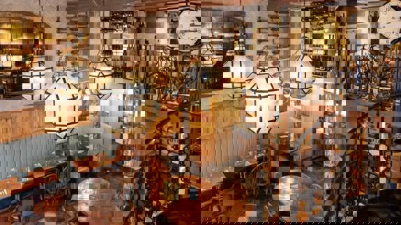 The cosy, multi-level interior of Stravaigin restaurant, featuring large geometric lantern light fixtures and a wrought iron spiral staircase.