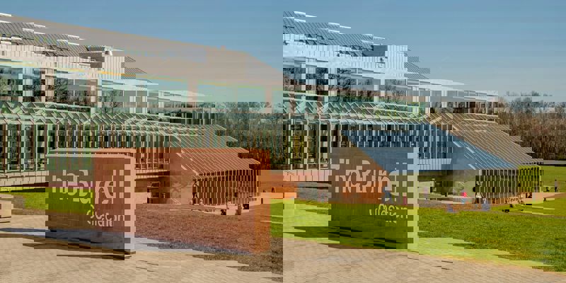 The modern glass and stone building of The Burrell Collection museum is shown under a clear sky.