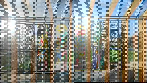 Sunlight streams through a series of four ornate stained-glass windows