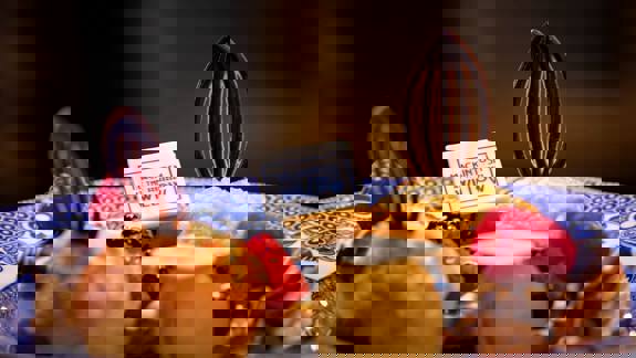 A plate with scones, jam, and intricate small cakes decorated with raspberries and chocolate on blue and white plates at the Mackintosh at the Willow.