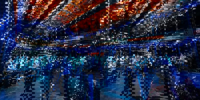 Dancers on the floor of Glasgow’s Old Fruitmarket, lit by string lights under the venue’s distinctive wooden roof.