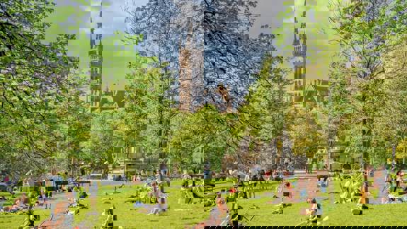 Kelvingrove Park: A park with people relaxing on the grass on a sunny day, with the University of Glasgow building visible in the background.