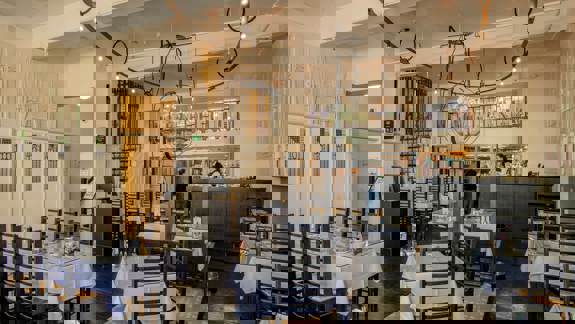 Inside "Mackintosh at the Willow," a beautiful tearoom adorned with the master's elegant Art Nouveau designs, featuring unique chairs, light fixtures, and decorative wall panels.