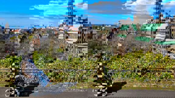 A person in a wheelchair overlooking the city of Glasgow, with the Glasgow Cathedral and a cityscape in the background.