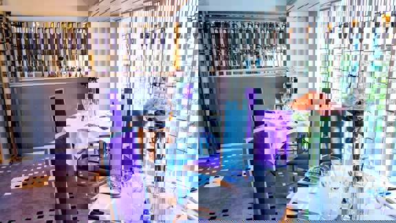 Elegant interior of Mackintosh at the Willow with purple chairs and rose bouquets on set tables, with distinct art nouveau stained glass windows.