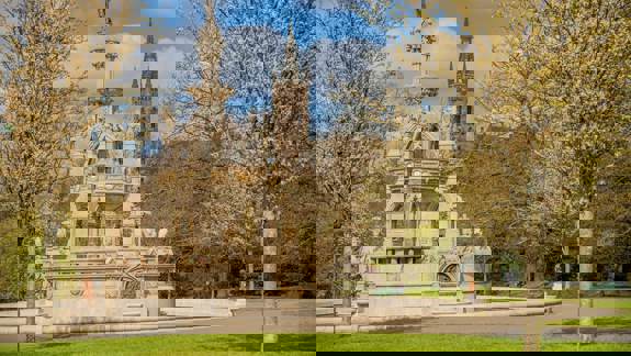 The Stewart Memorial Fountain in Kelvingrove Park with the Glasgow University main building's spire visible in the background.
