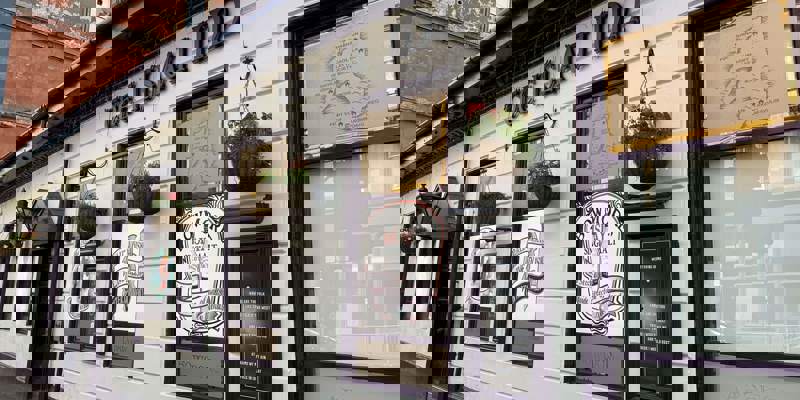 The exterior of the Islay Inn, a white building with window signs for Bowmore and Ardbeg whisky.