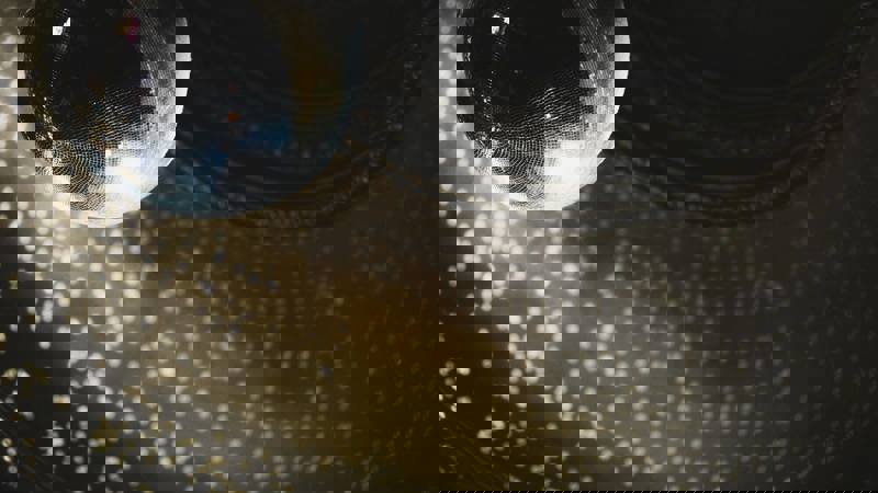 A large, mirrored disco ball hangs from the ceiling, reflecting light in a pattern of small, bright dots.