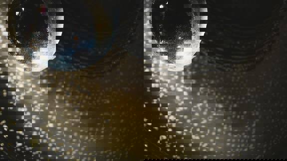 A large, mirrored disco ball hangs from the ceiling, reflecting light in a pattern of small, bright dots.