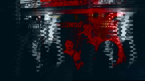 Singer performing under red lighting at The Howlin’ Wolf music bar, watched by an intimate audience.