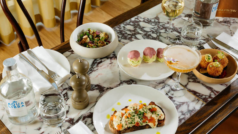 Marble table set with small plates, salad bowls, and wine glasses.