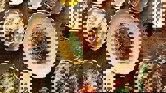 An overhead shot of a dining table with multiple dishes, including a large plate of roasted meat, bread, and various appetizers.