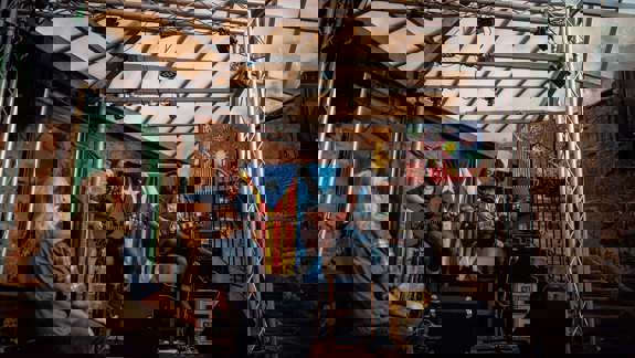 Musicians perform live acoustic set inside a rustic venue with a Che Guevara portrait, Scottish and Catalan flags, and a small, attentive audience under a glass roof.