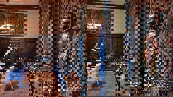 A gallery room displays a suit of armour, tapestries, and other artefacts.