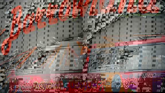 Eddi Reader waves from the top deck of a red City Sightseeing Glasgow tour bus. In the background, large red neon letters spell out "Barrowland."