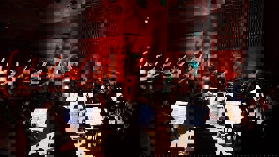 A wide shot of a stage at the Royal Conservatoire of Scotland where a live orchestra plays for ballet dancers.