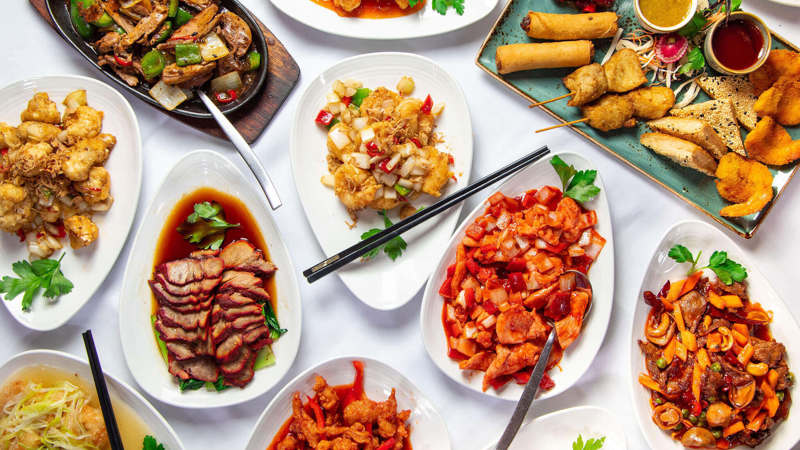 A table filled with various Chinese dishes including fried items, meats, and vegetables.