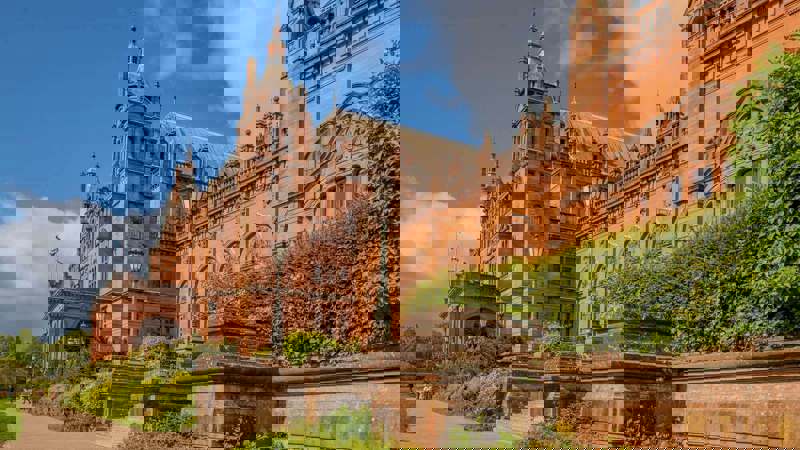 Exterior view of the ornate, red sandstone Kelvingrove Art Gallery and Museum under a blue sky.