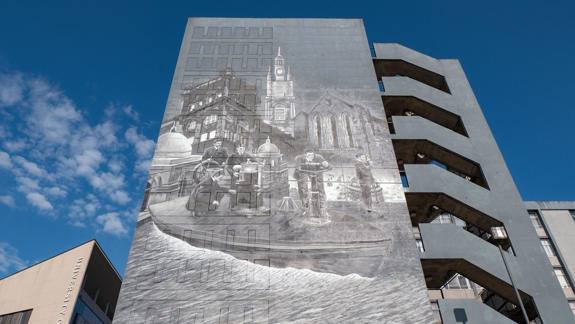 Large grayscale mural on a university building depicting historical figures on a boat and architectural elements.