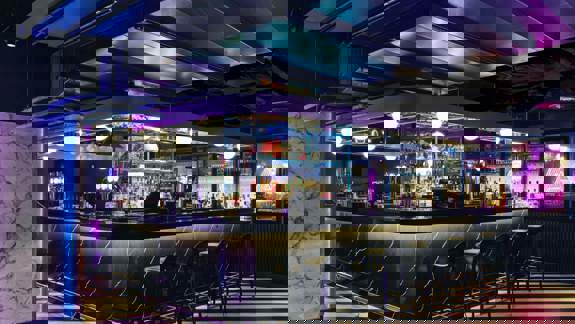 Black marble bar with neon lights and striped floor.