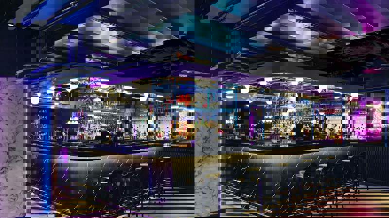 Black marble bar with neon lights and striped floor.